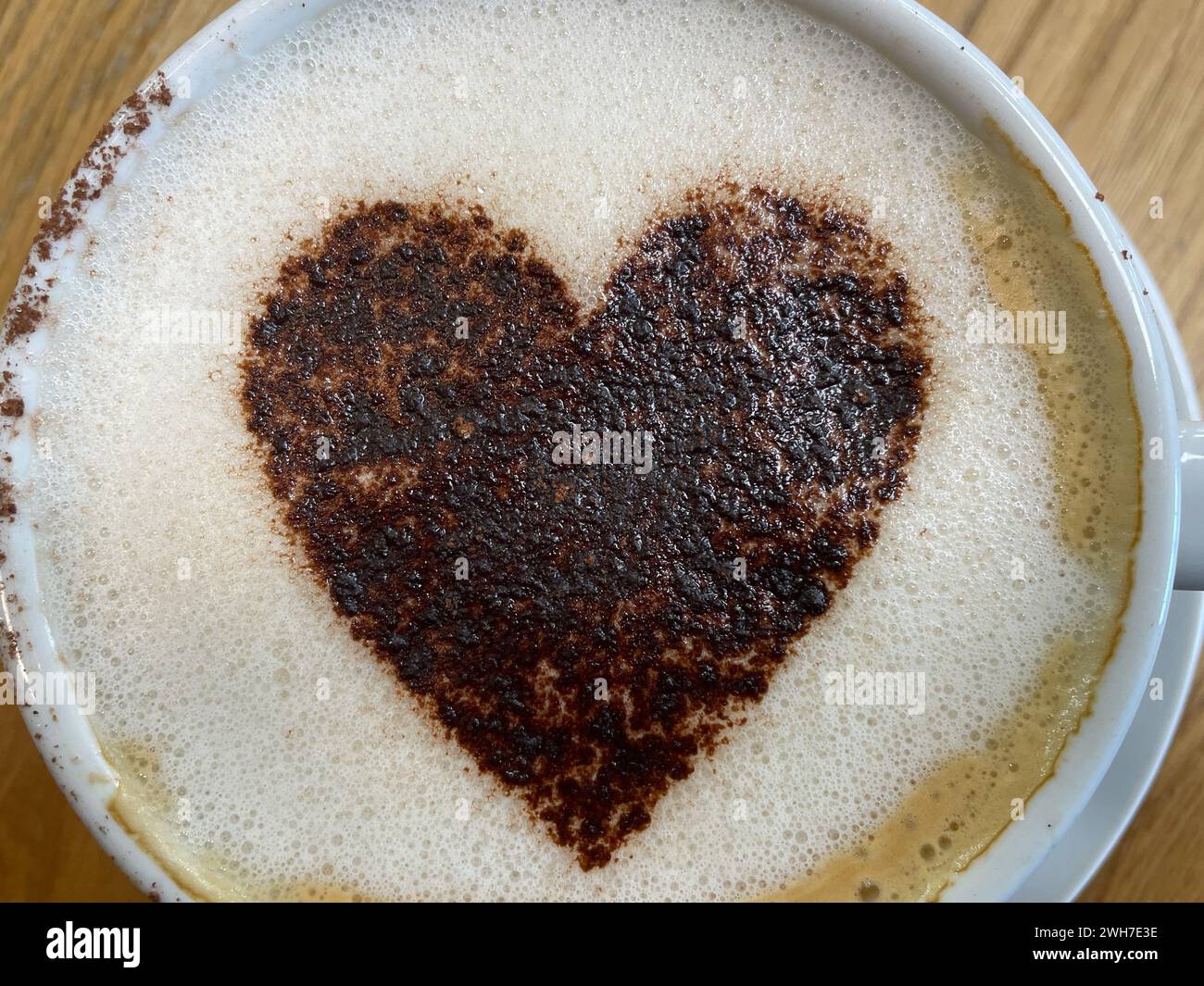 Blick von oben auf einen schäumenden Kaffee mit einem Herzsymbol aus Schokoladenstreuseln. Romantisch Stockfoto