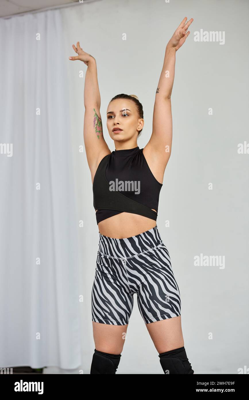 Eine anmutige Tänzerin in einem auffälligen Outfit spielt eine dynamische Choreografie, während sie ihre Hände hebt Stockfoto