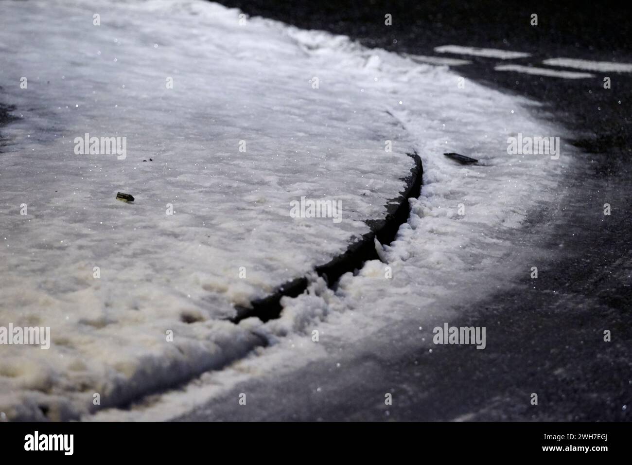 Glatte Eis und verdichteten Schnee bedeckten Pfad unter Straßenlaternen nachts im Vereinigten Königreich Stockfoto