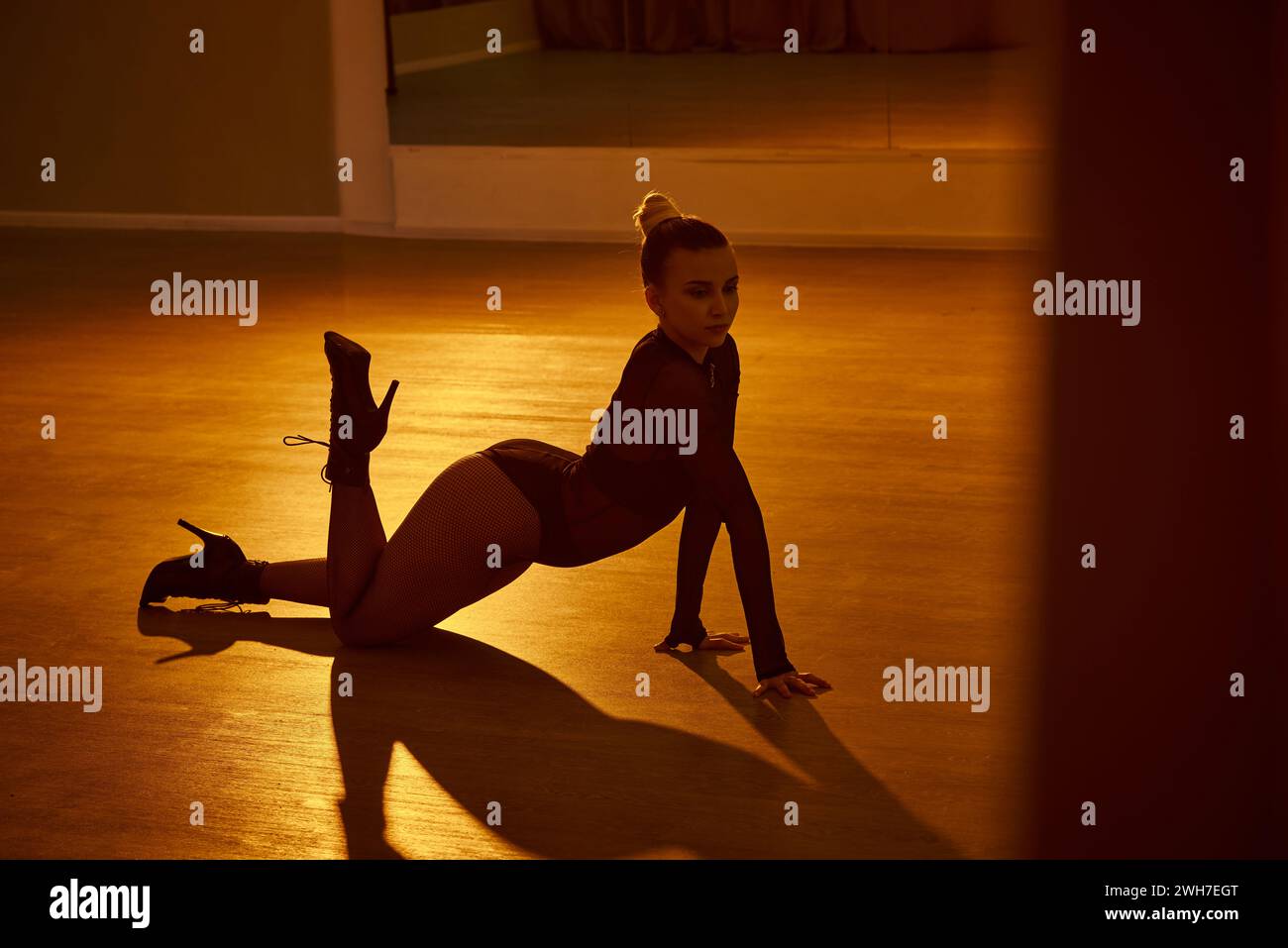 Die ausgeglichene Frau zeigt Anmut und Stärke in einer Tanzposition, ihre High Heels sind fest auf dem Boden platziert Stockfoto