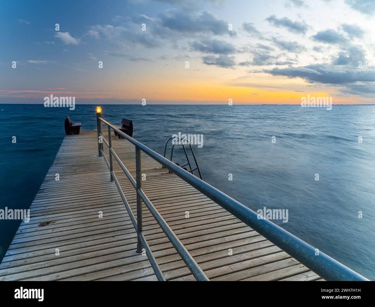 Holzsteg in der Dämmerung und leuchtenden Pfosten auf Fehmarn Stockfoto