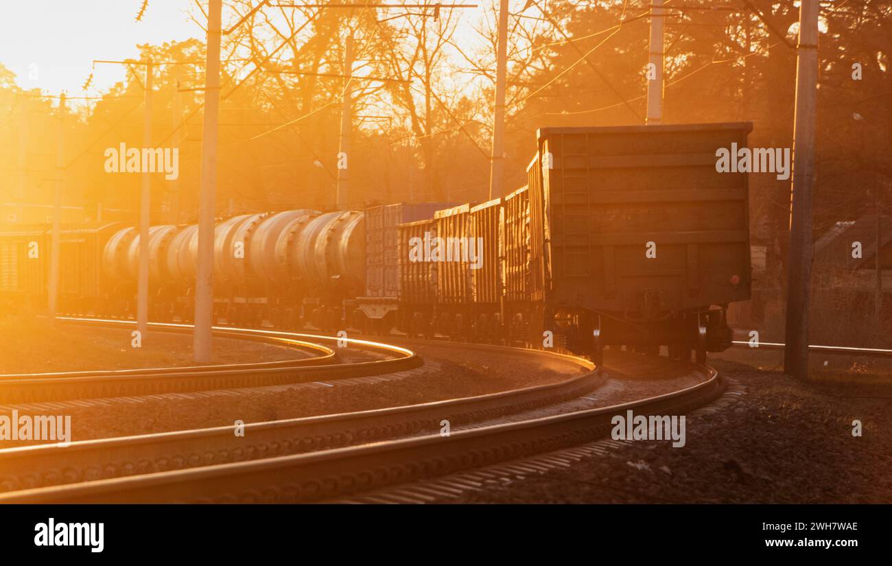 Industrielandschaft eines Güterzuges auf einer Eisenbahn bei Sonnenuntergang. Transport schwerer Lasten. Frachttransport. Stockfoto