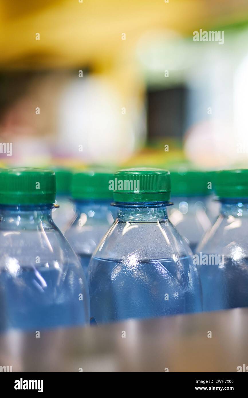 Blaue halbstündige Mineralwasserflaschen aus Kunststoff mit grünem Deckel im Lager, Supermarktregel, Nahaufnahme. Hoher Kunststoffverbrauch in EV Stockfoto
