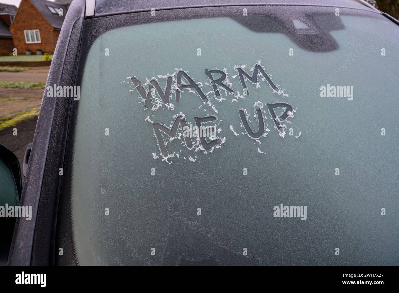 „Warm Me Up“-Nachricht, die im Dezember 2023 in West Sussex, England, mit einem Finger auf eine eisige Windschutzscheibe geschrieben wurde. Stockfoto