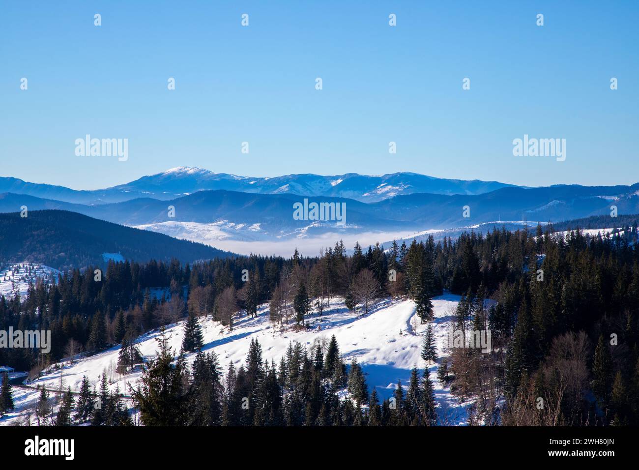 Schneebedeckte Berge mit Wolken und Nebel von oben betrachtet Stockfoto