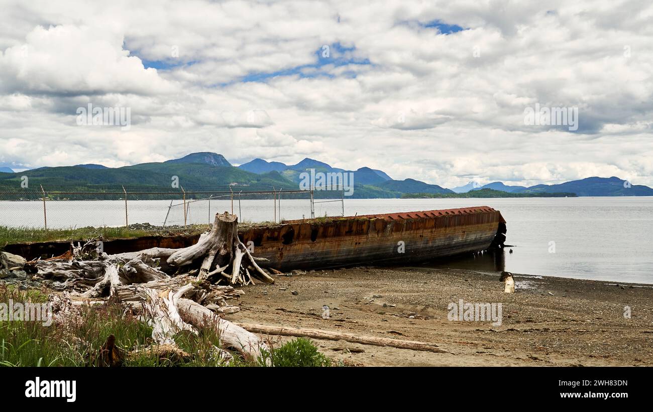 Alter, rostiger Schiffsrumpf am Strand, der als Wellenbrecher benutzt wird. Stockfoto