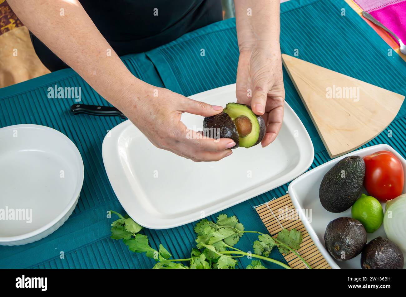 Hände, die Guacamole mit Reifen Avocados herstellen. Eine Bilderserie zeigt Hände, die Avocados akribisch in eine cremige Delikatesse verwandeln Stockfoto
