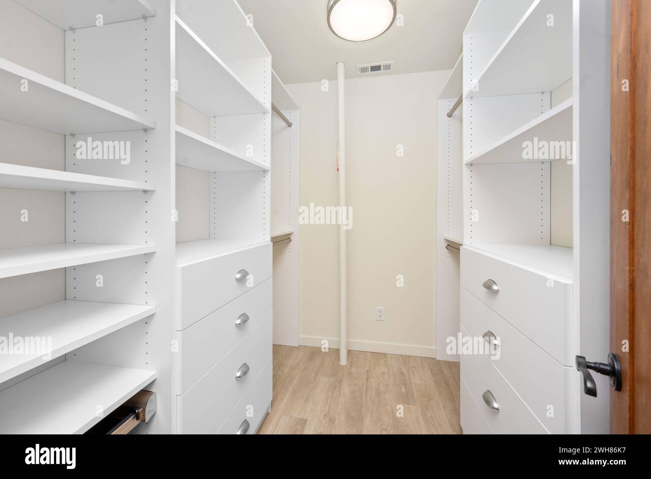 Offener Schrank mit weißen Schubladen und Einlegeböden auf beiden Seiten Stockfoto