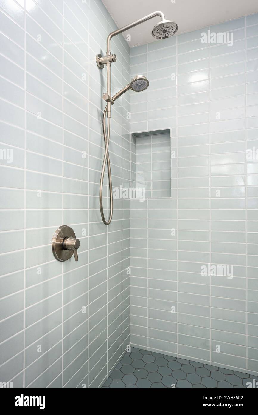 Duschkopf gegen hellblaue Fliesen, grauer Fliesenboden Stockfoto
