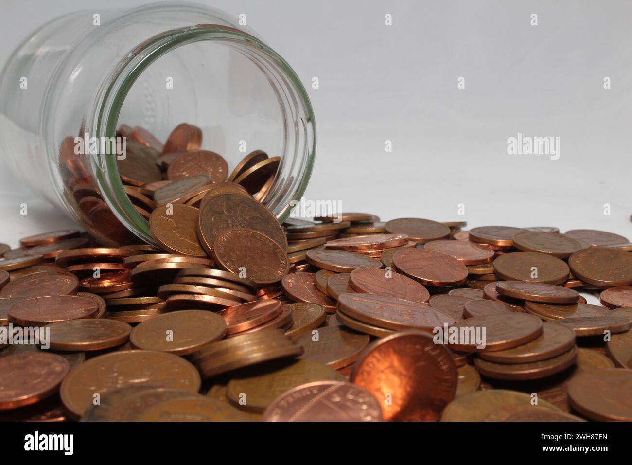 Britische ein- und zwei-Pence-Münzen fallen aus einem Glas Stockfoto