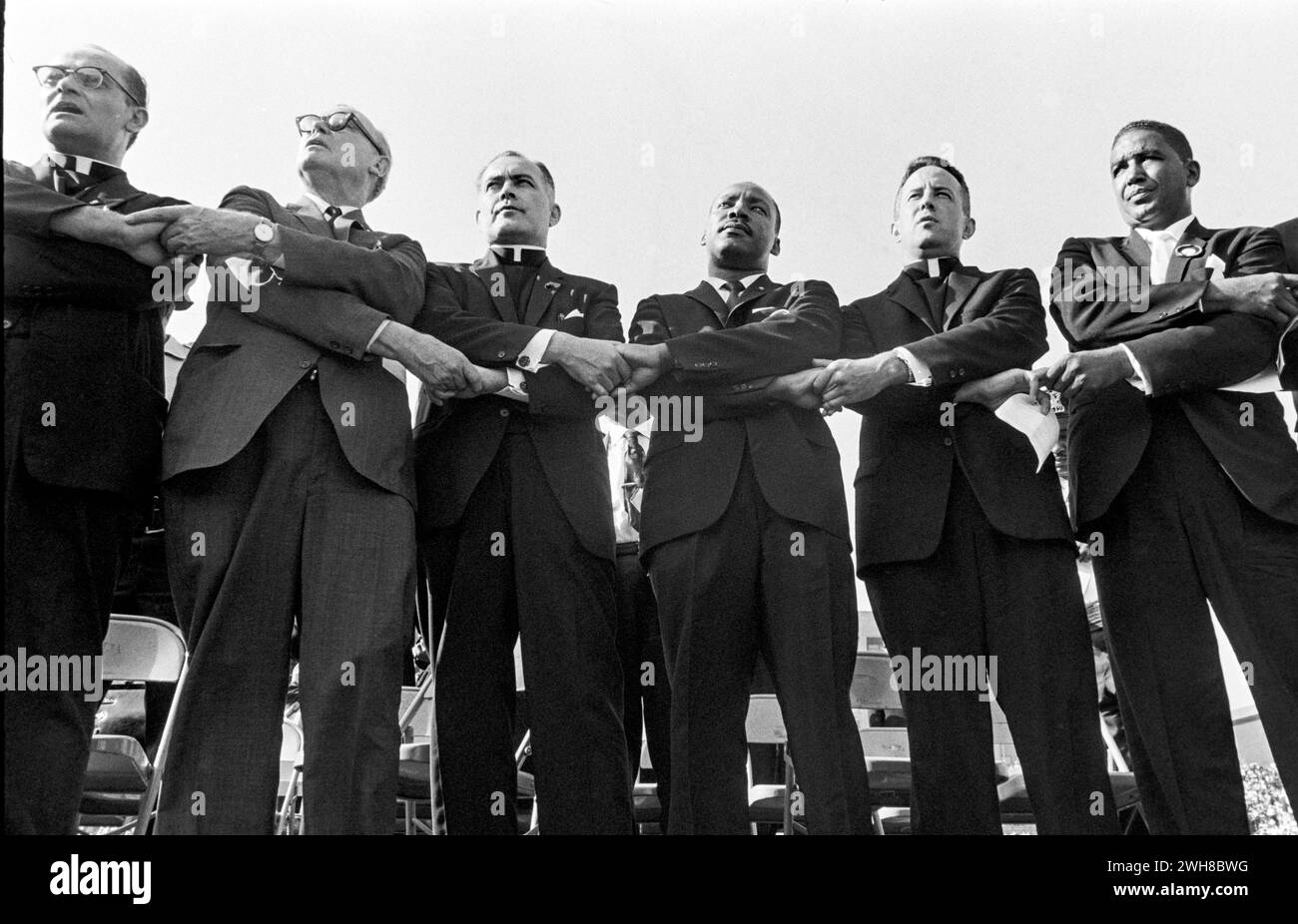 United Front: Dr. Martin Luthur King mit diverser Gruppe von Männern, die sich bei Daytime Event an die Hand nehmen Stockfoto