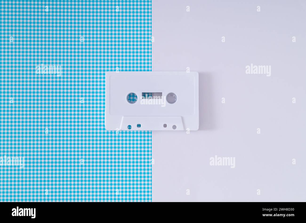 Layout des weißen Retro-Audiokassettenbands auf weißem und blauem Hintergrund. Kreatives Konzept der alten Technologie. Ästhetik der 80er Jahre. Vintage-Audiokassette Stockfoto