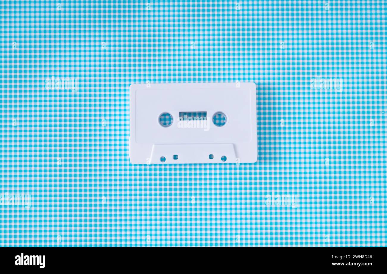 Layout des weißen Retro-Audiokassettenbands auf weißem und blauem Hintergrund. Kreatives Konzept der alten Technologie. Ästhetik der 80er Jahre. Tip für Vintage-Audiokassetten Stockfoto
