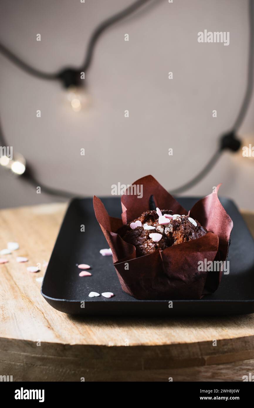 Schokoladenmuffin mit Herzen auf dunklem Hintergrund. Stockfoto