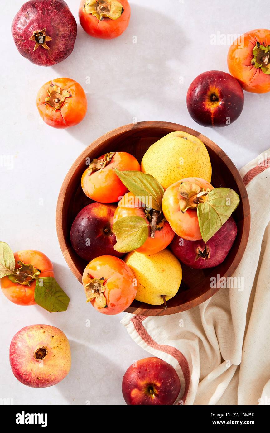 Granatäpfel, Persimmonen, Birnen und Äpfel in einer Schüssel auf neutralem Hintergrund Stockfoto