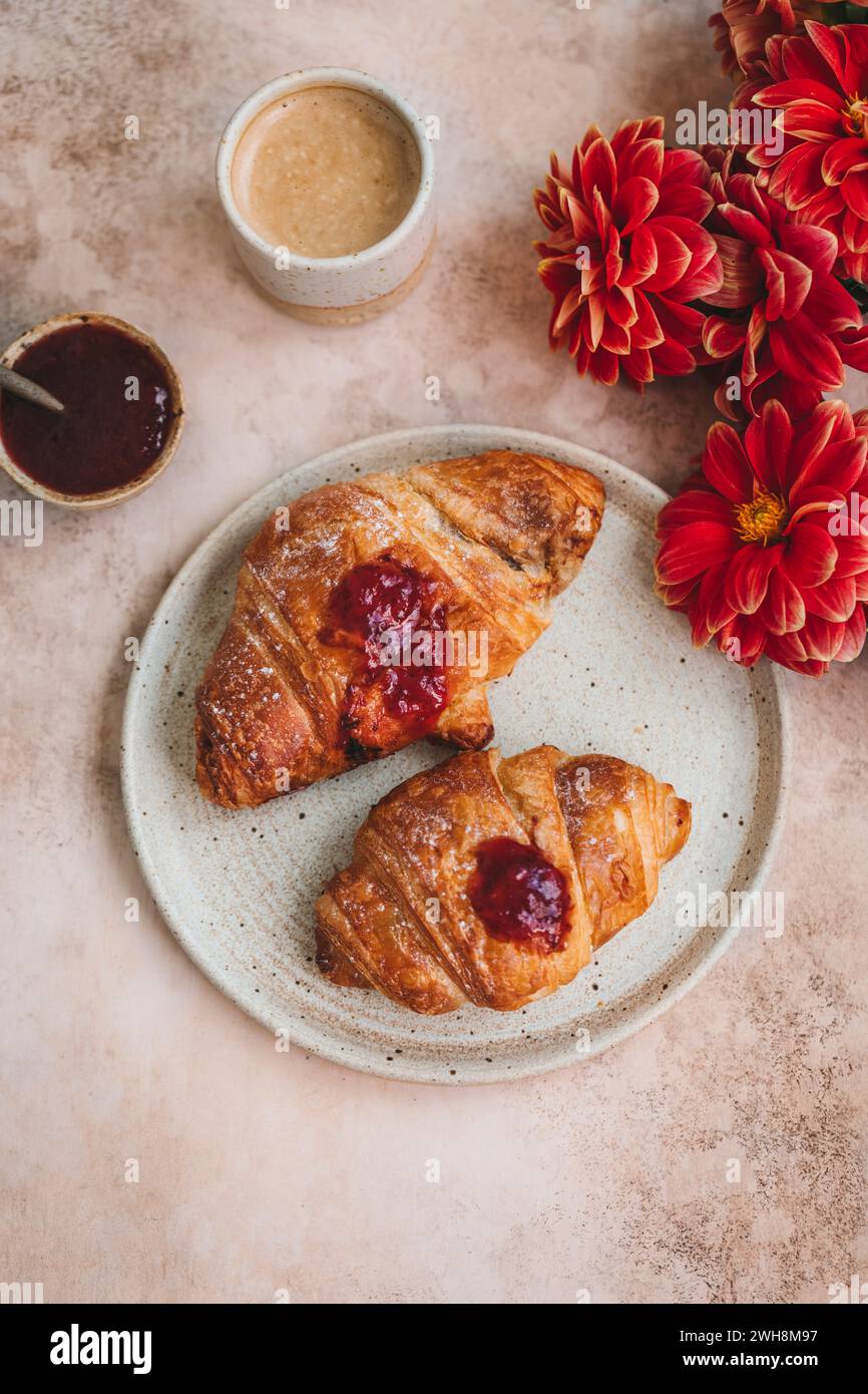 Croissants mit Erdbeermarmelade auf Keramikplatte Stockfoto