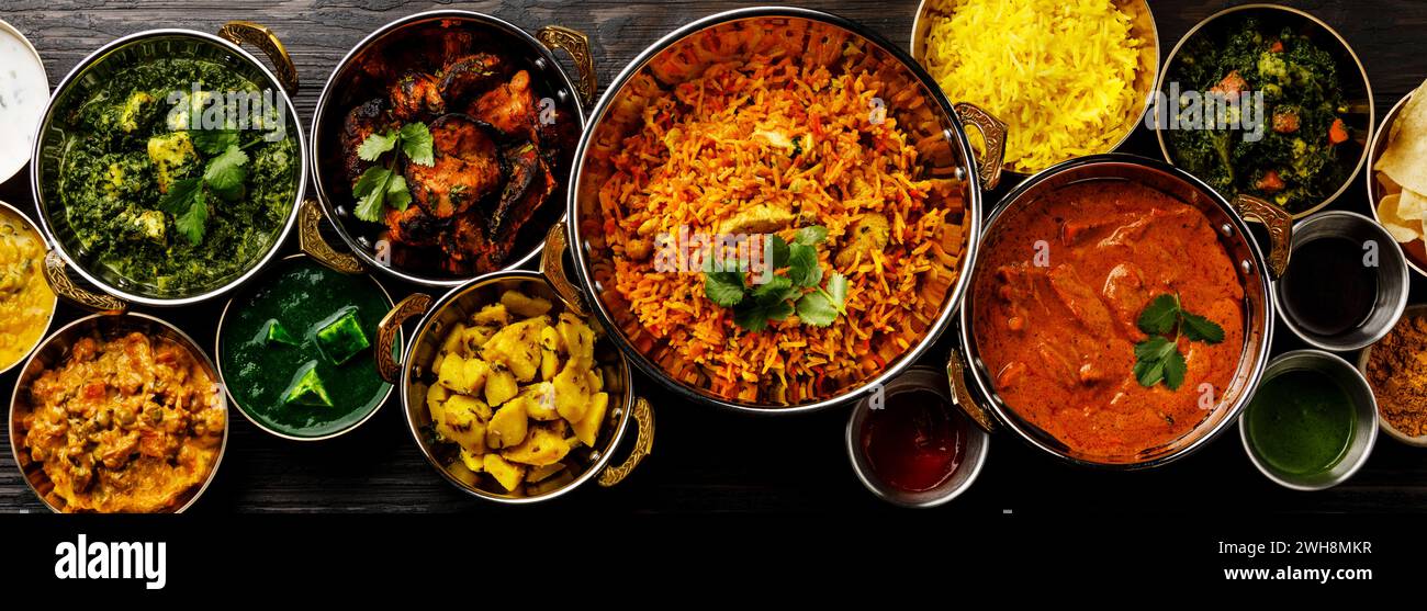 Indisches Essen Curry Butter Huhn, Palak Paneer, Chiken Tikka, Biryani, Gemüse Curry, Papad, Dal, Palak Sabji, Jira Alu, Reis mit Safran auf dunklem B Stockfoto