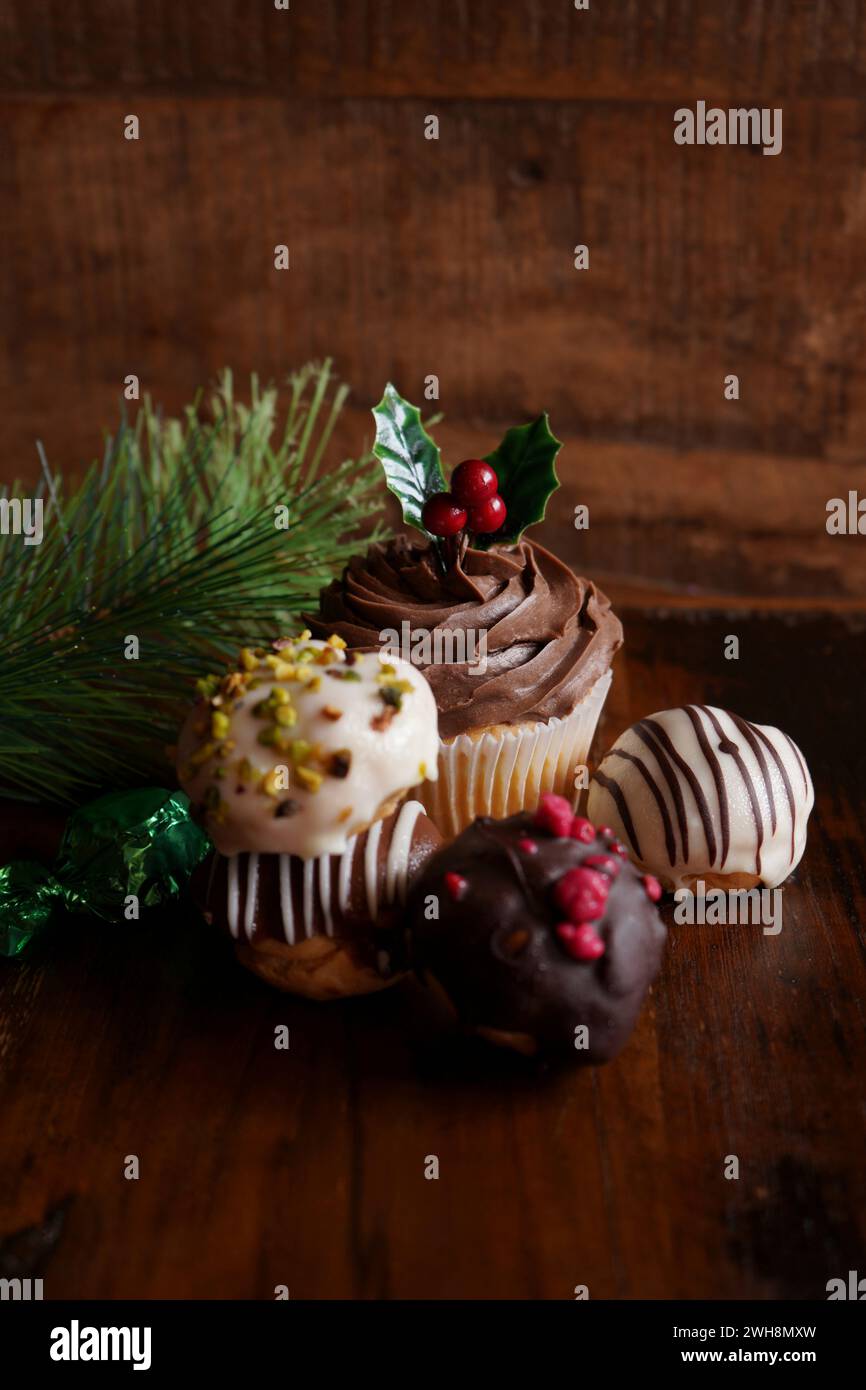 Weihnachtsfeiertage Schokoladentörtchen und Profiteroles vor dunklem Holzhintergrund, mit Kopierraum. Stockfoto