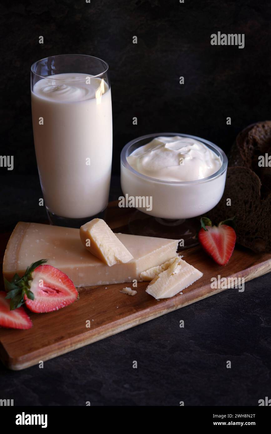 Gesunde probiotische Molkerei, einschließlich Kefir, griechischem Joghurt und Parmgiano reggiano Käse vor dunklem Hintergrund. Stockfoto