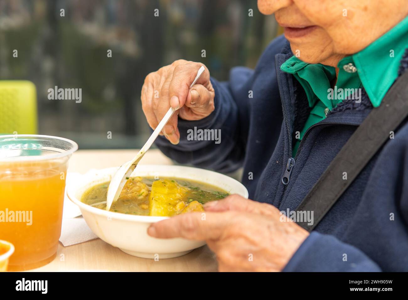 Eine nicht erkennbare Seniorin, die eine Suppe am Tisch hat Stockfoto