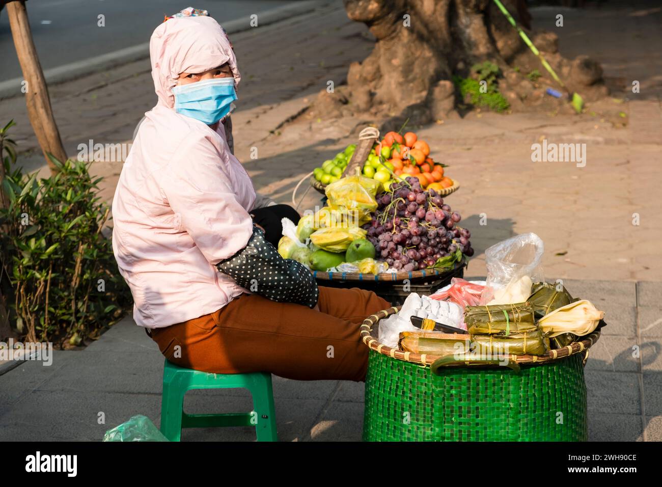 Frau mit Gesichtsmaske, die frisches Obst auf den Straßen von Hanoi, Vietnam, verkauft Stockfoto