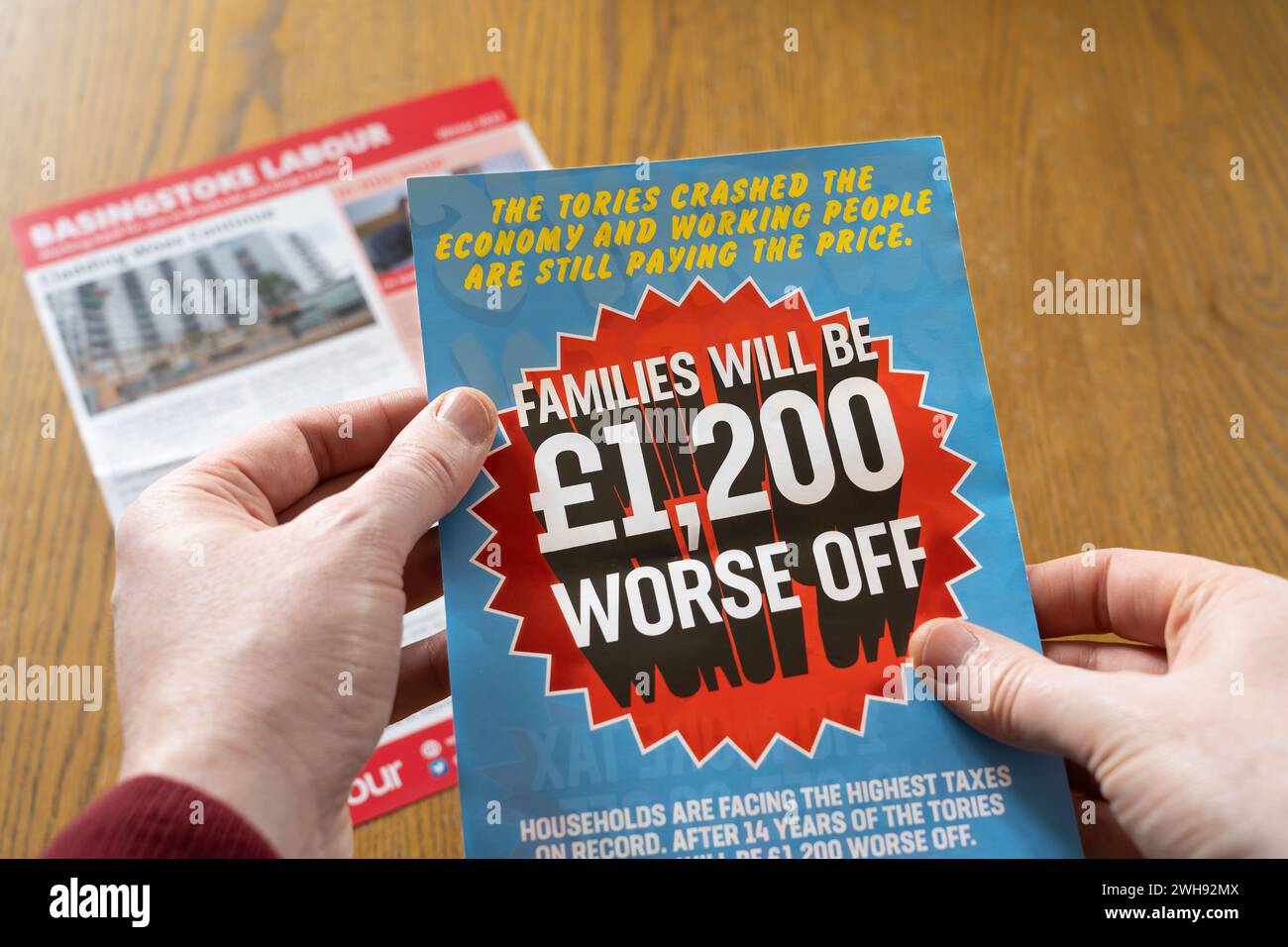 Die Hand eines Mannes hält einen Flyer von der Labour Party in Basingstoke, in dem behauptet wird, dass Familien 1.200 Pfund schlechter dran sind, seit die Tories die Wirtschaft stürzten. UK Stockfoto