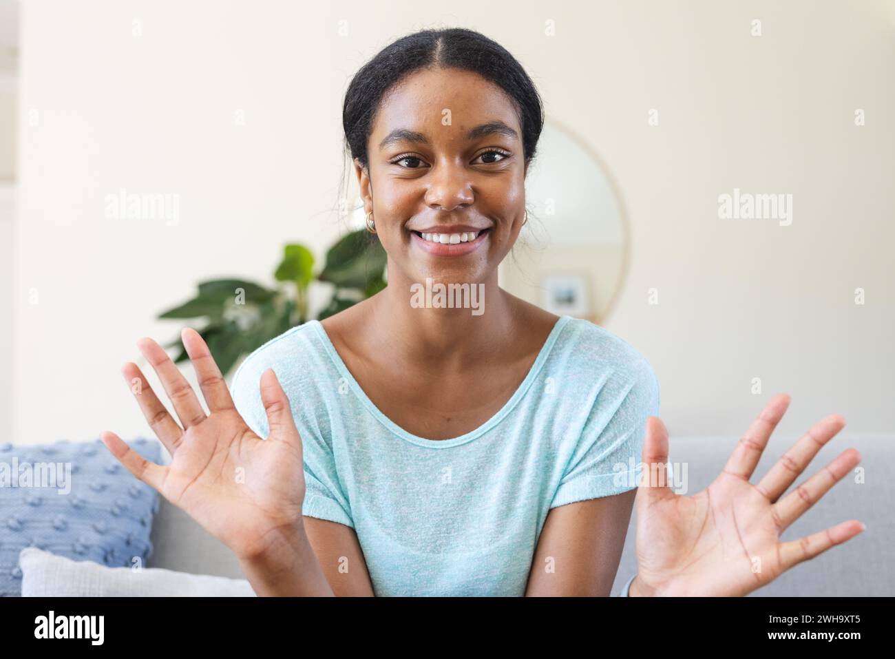 Eine junge Frau mit birassischer Rasse lächelt bei einem Videoanruf zu Hause hell Stockfoto