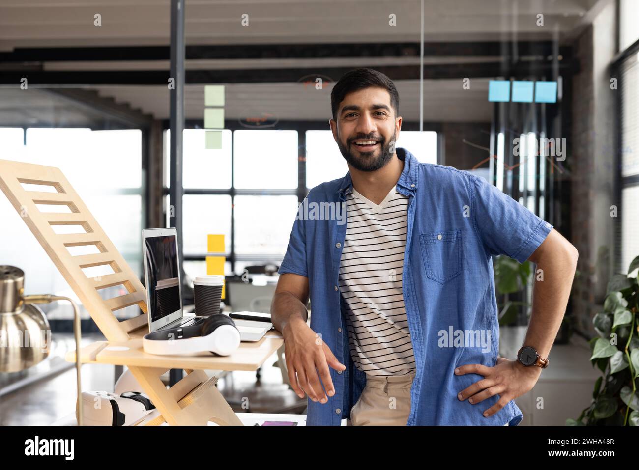 Ein junger asiatischer Mann steht selbstbewusst in einem modernen Büro, gekleidet in legere Geschäftskleidung Stockfoto