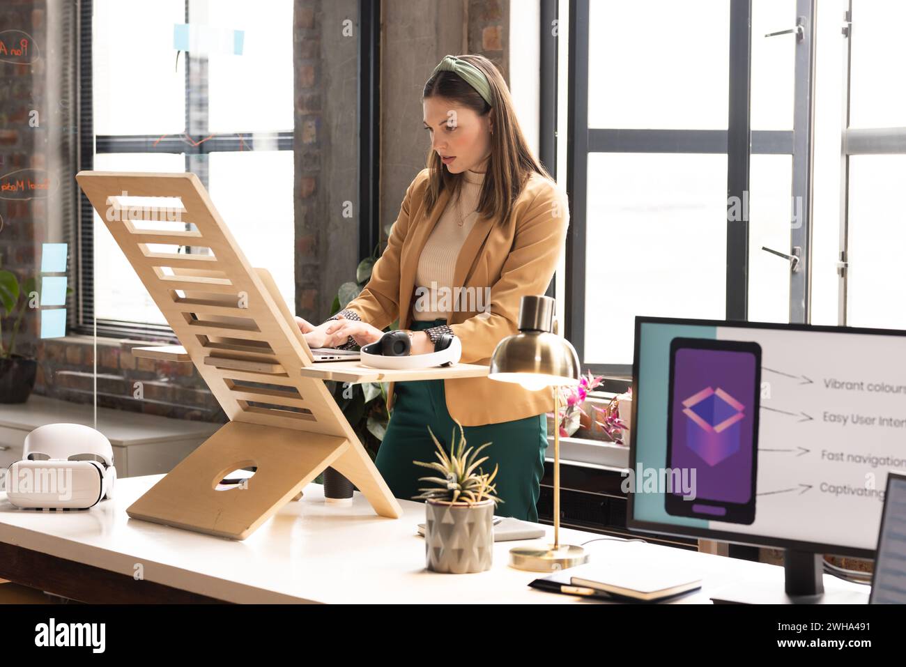 Die junge kaukasische Frau arbeitet an einem zwanglosen Bürotisch in einem Büro Stockfoto