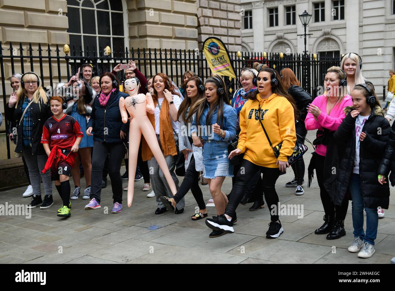 September 2018. Eine Frau hält eine Puppe in die Luft, während eine stille Disco-Party heute ihren Weg durch die Straßen von Liverpool macht. Stockfoto