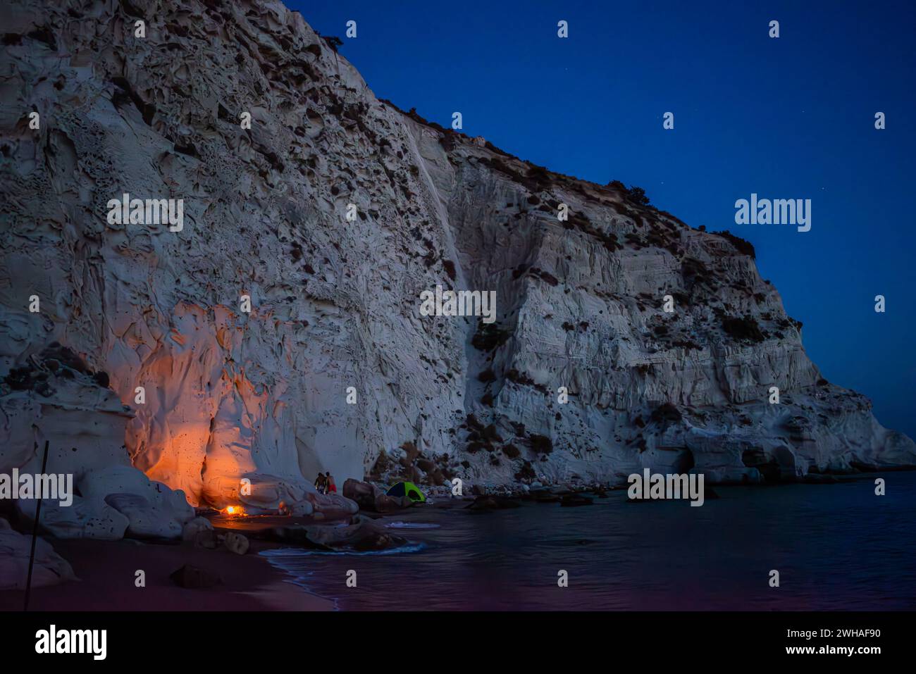 Camping Licht unter dem Abendhimmel, eingebettet von Berg und Meer, schafft eine ruhige und einladende Atmosphäre für eine Nacht in der freien Natur. Stockfoto