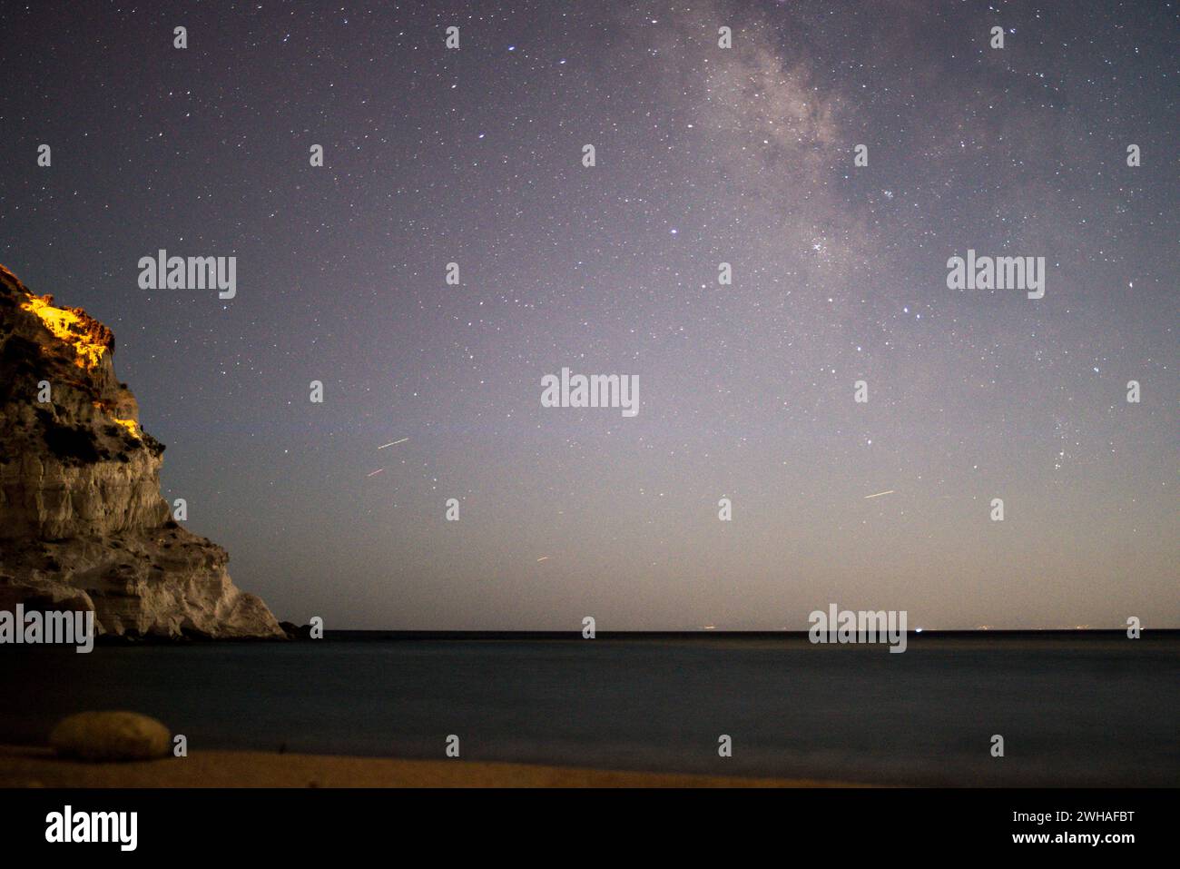 Eine atemberaubende Küstenszene, während die Milchstraße den Nachthimmel über dem Meer und den Bergen schmückt und ein heiteres und kosmisches Wunder schafft. Stockfoto