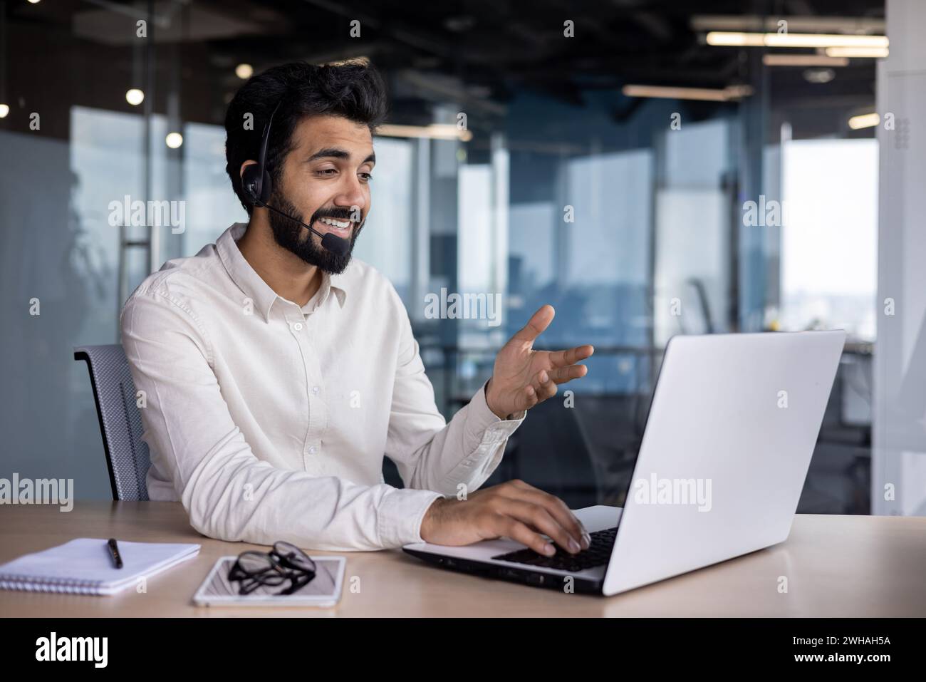 Junger indischer Unternehmer, der aktiv an einer Videokonferenz in einem modernen Büroumfeld teilnimmt und Professionalität zum Ausdruck bringt. Stockfoto