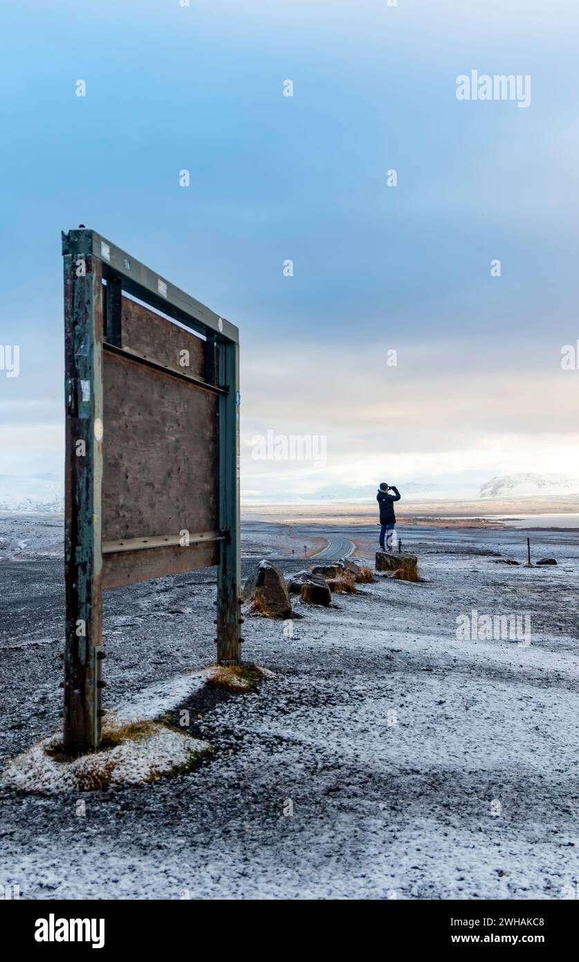 Anonyme Person, die auf gefrorener Landschaft steht und die Natur in der Nähe des Seeufers bei kaltem Wetter vor blauem Himmel bewundert Stockfoto