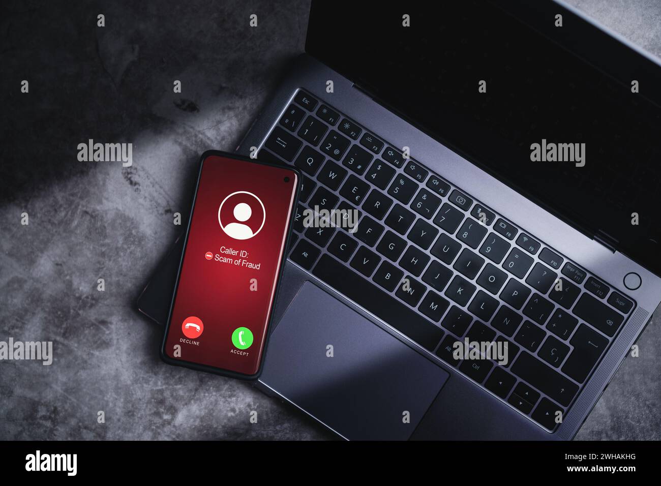 Smartphone empfängt unerwünschte Anrufe, während es sich auf dem Laptop ruht. Konzept für Spam, Betrug, Phishing und Betrug. Sicherheitstechnologie. Stockfoto