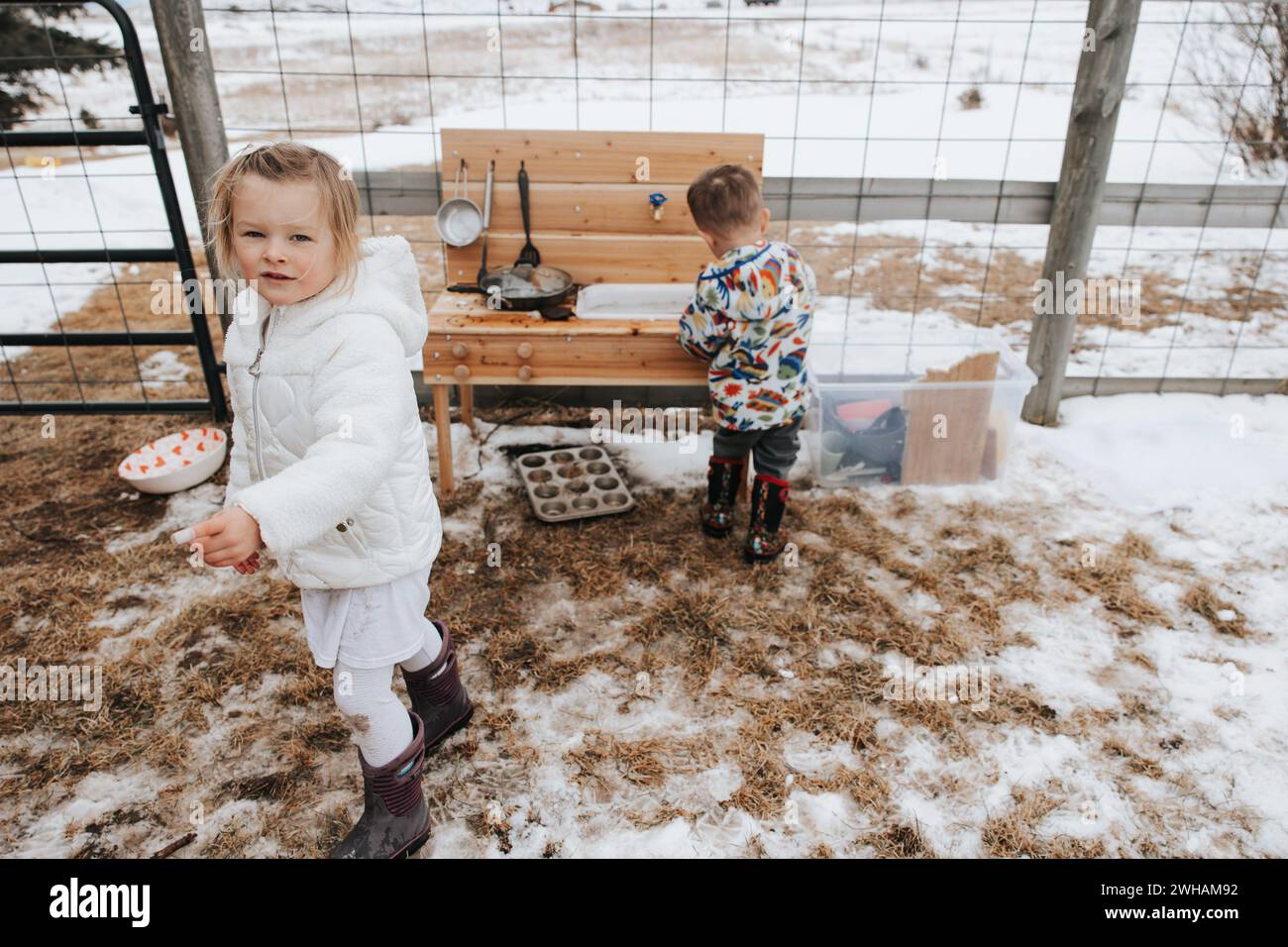 Geschwister spielen in der verschneiten Schlammküche, Winterspaß Stockfoto