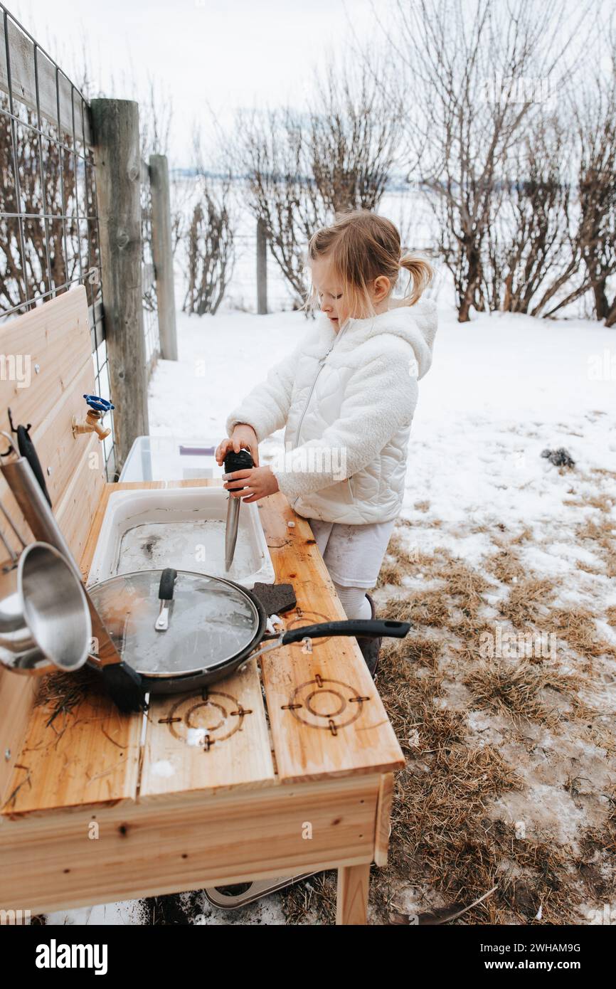 Kreatives Mädchen mit Schnee in der Schlammküche im Freien Stockfoto