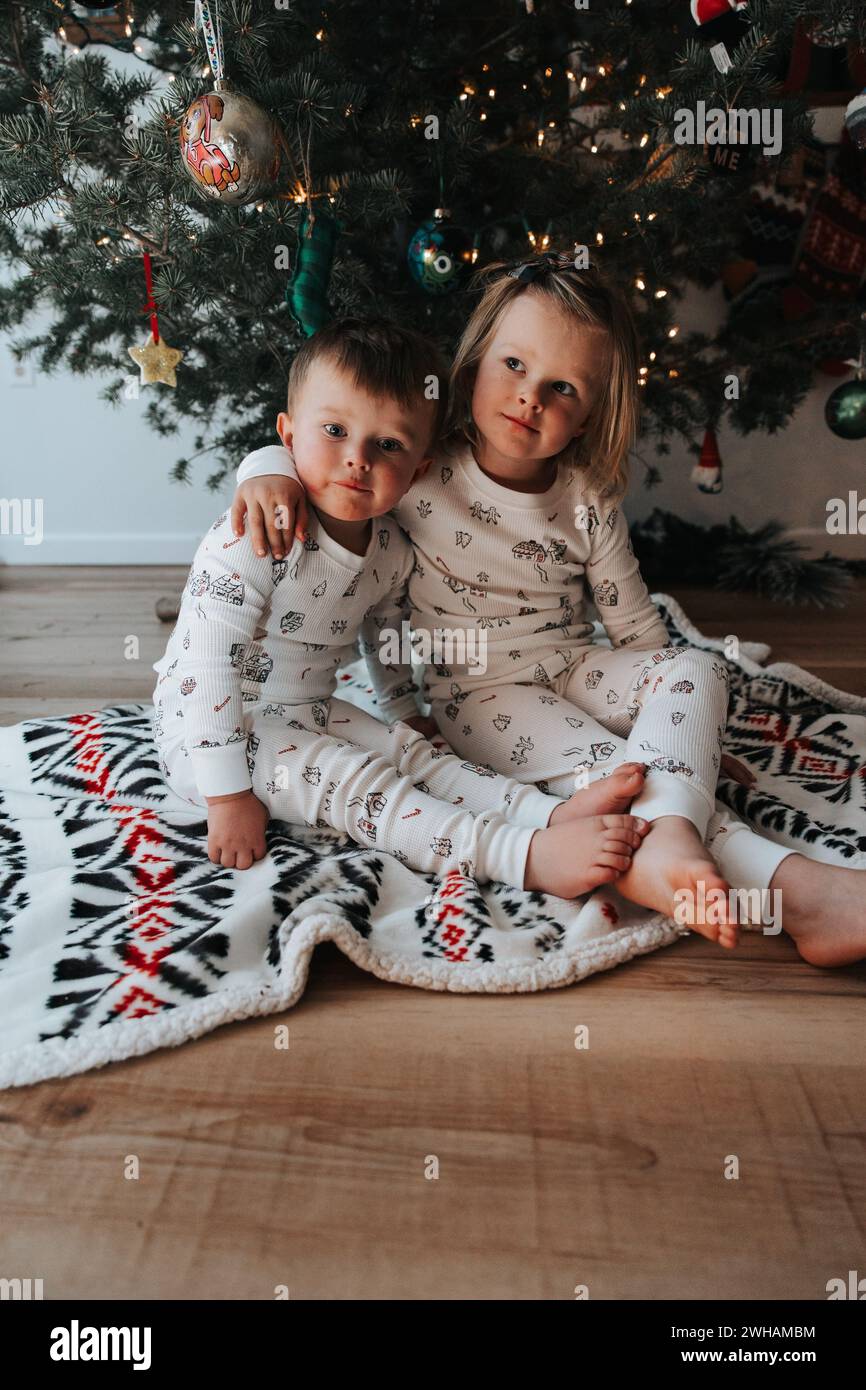 Geschwister im passenden Pyjama, weihnachtliche Umarmung Stockfoto