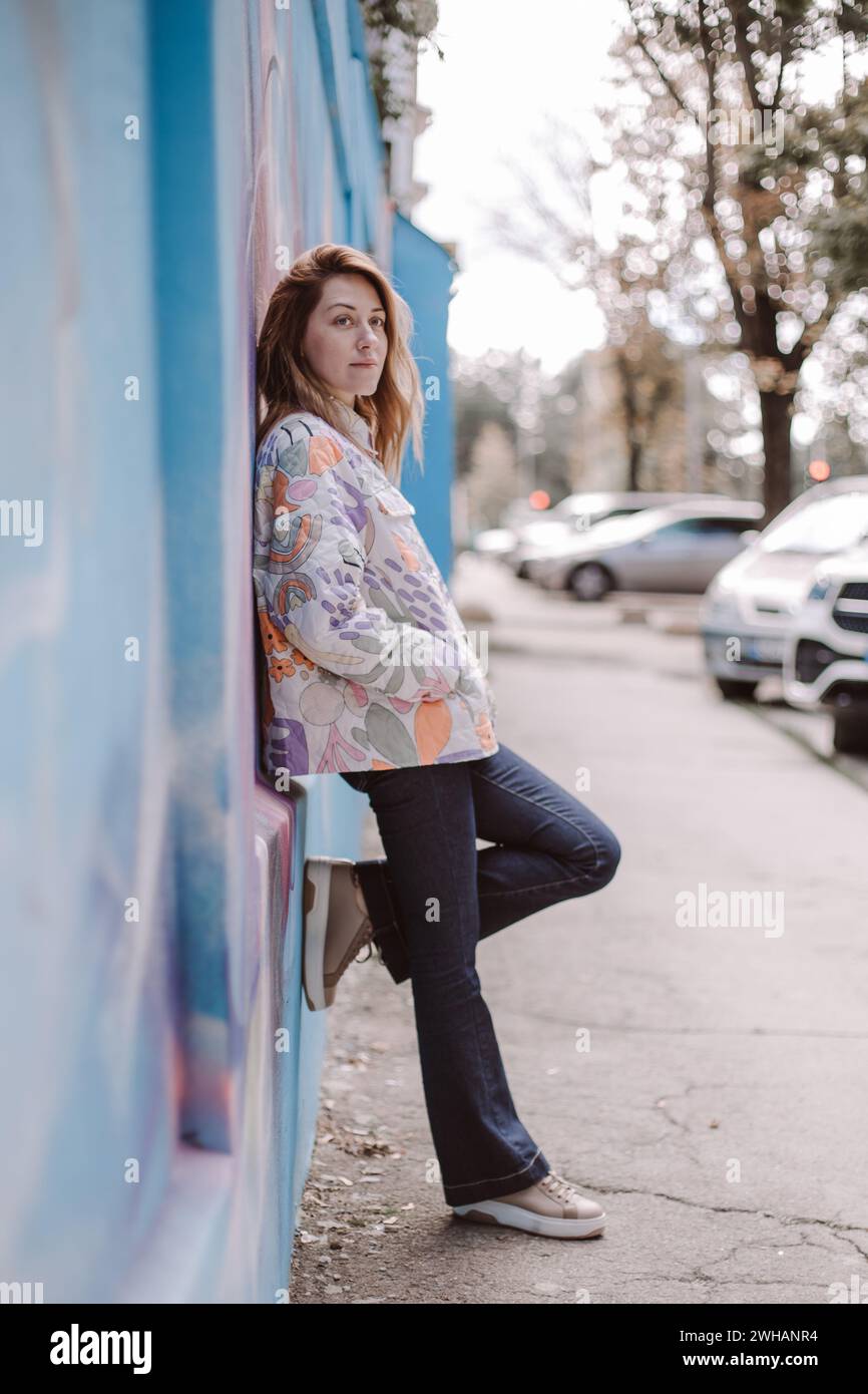 Frau in legeren Klamotten in der Nähe der Wand auf der Straße Stockfoto