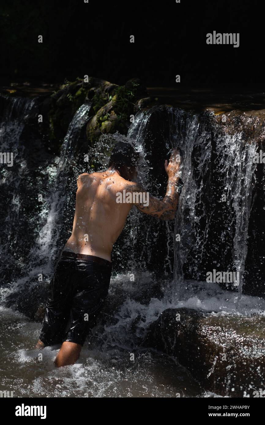 Junger tätowierter Mann am tropischen Wasserfall auf Bali Island. Stockfoto