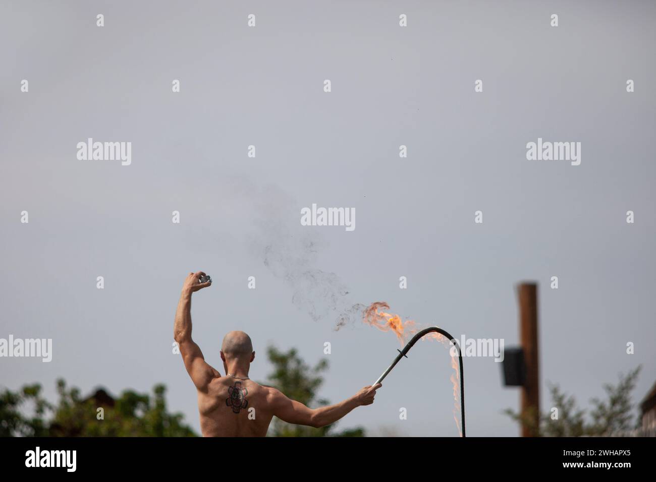 Hinter dem Blick auf einen muskulösen Glatzen mit flammender Peitsche Stockfoto