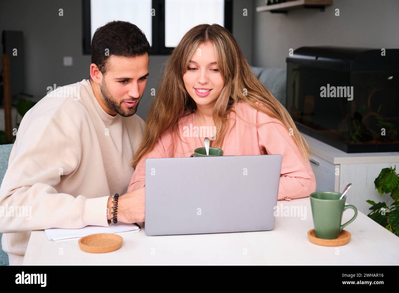 Spanisches Paar benutzt den Laptop zusammen, während er Kaffee trinkt. Stockfoto