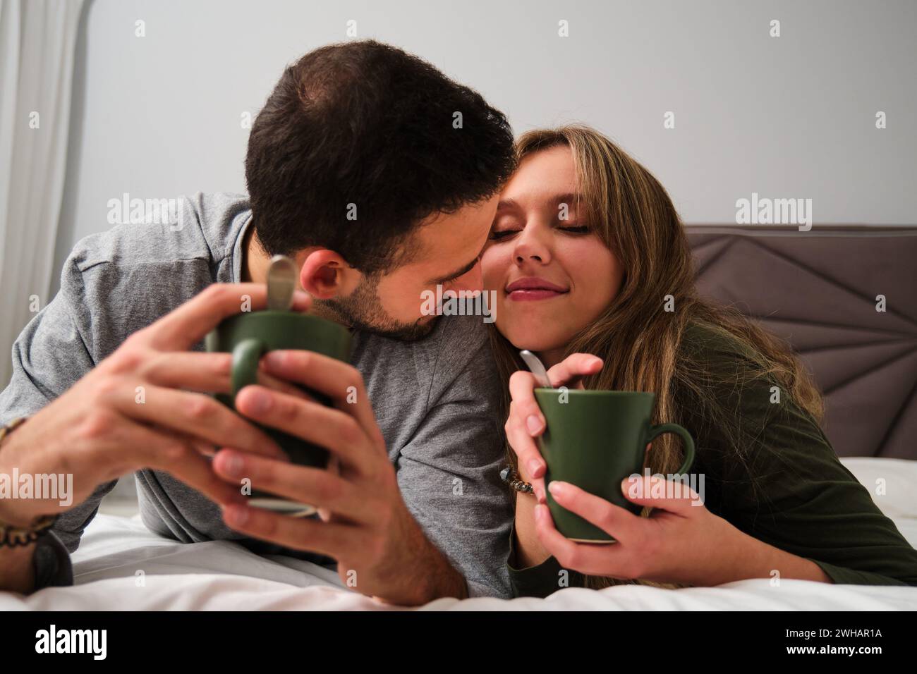 Verliebtes spanisches Paar trinkt Kaffee im Bett. Stockfoto