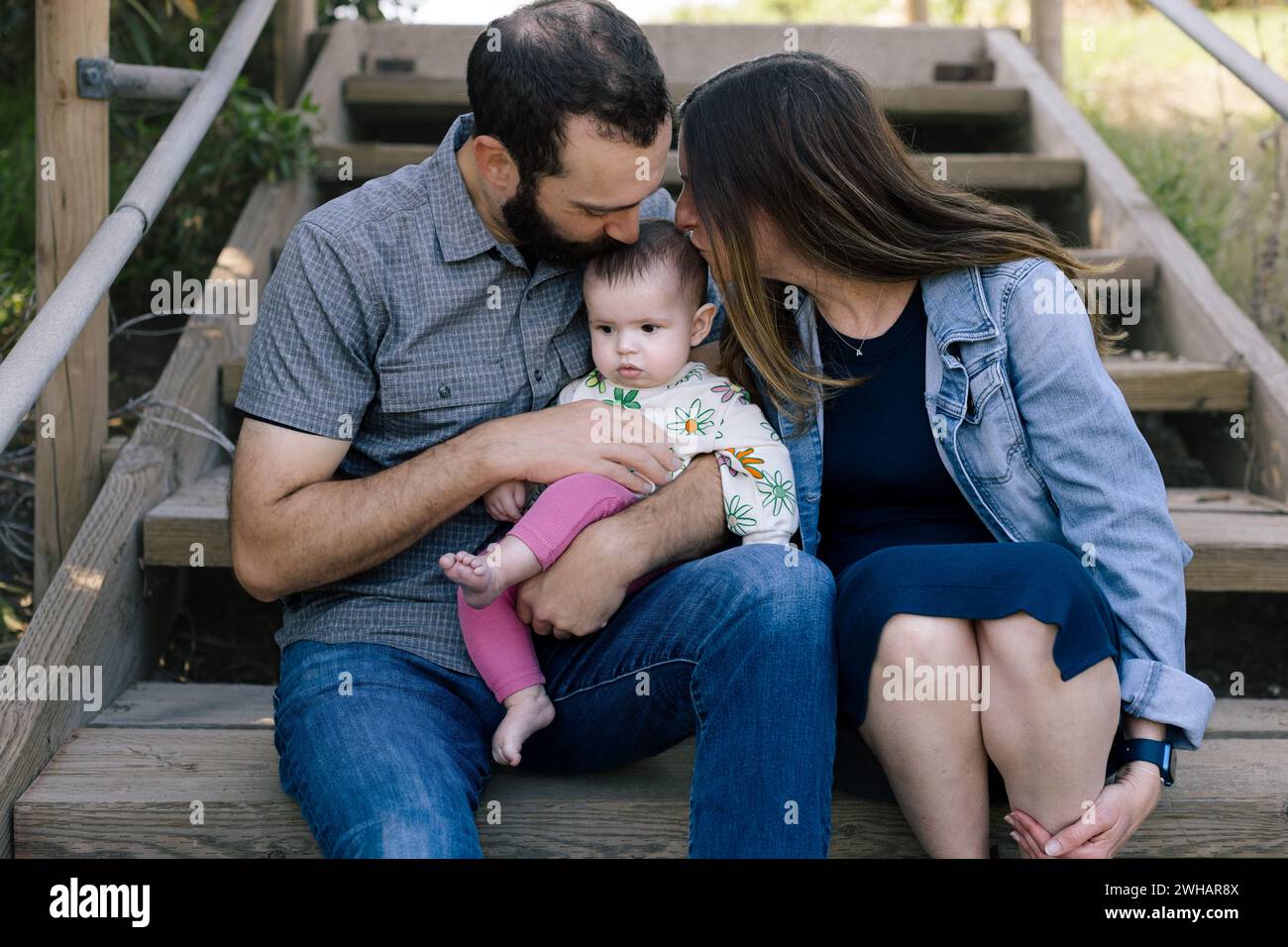 Mutter und Vater küssen den Kopf der Kleintochter Stockfoto