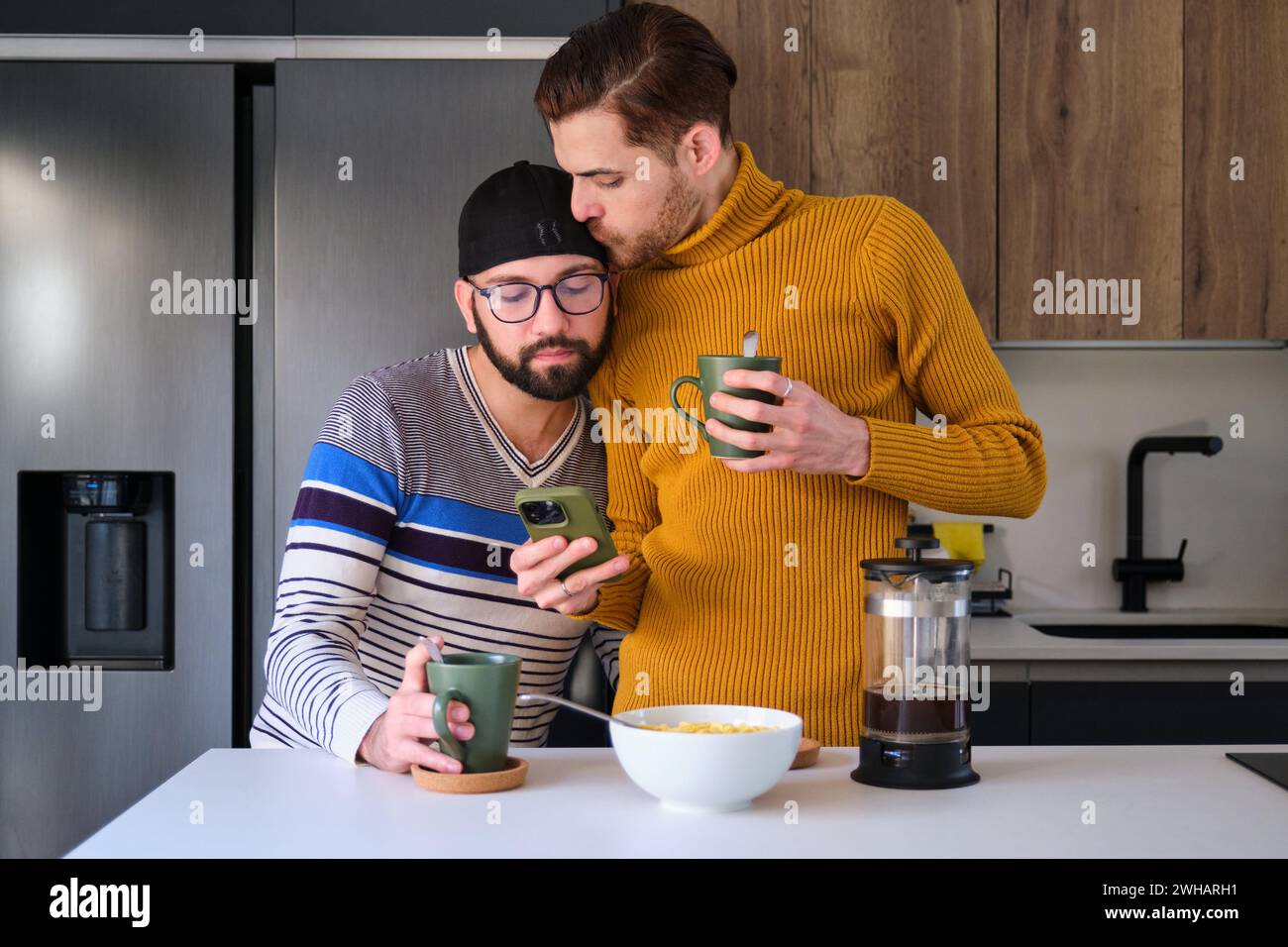 Homosexuelles Paar küsst, telefoniert und frühstückt. Stockfoto