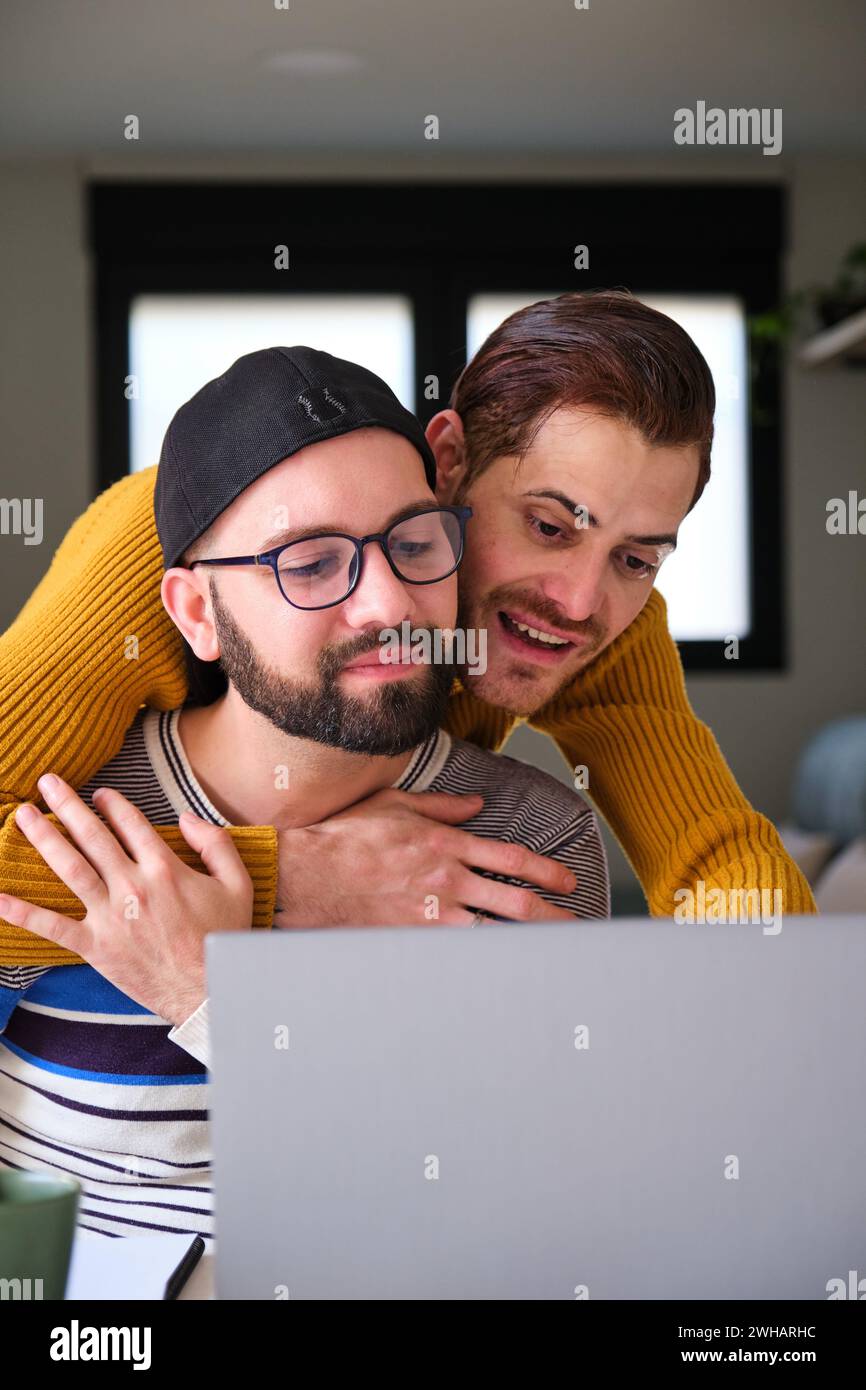 Homosexuelles Paar, das den Laptop zusammen umarmt. Stockfoto