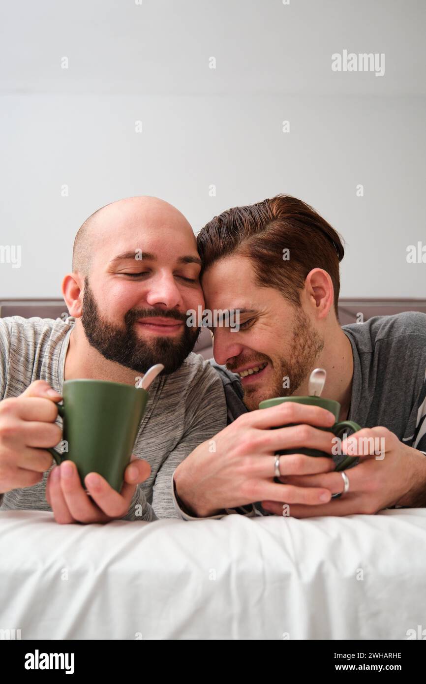 Verliebtes schwules Paar trinkt Kaffee im Bett. Stockfoto