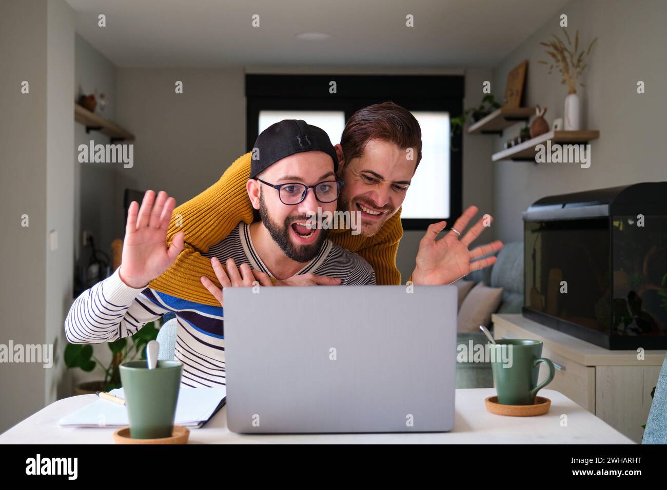 Homosexuelles Paar, das bei einem Videogespräch mit Familie oder Freunden winkt. Stockfoto