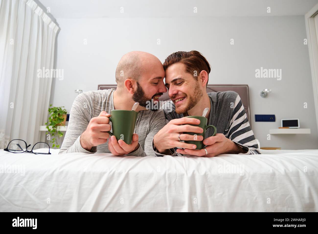 Homosexuelles verliebtes Paar trinkt Kaffee zusammen im Bett. Stockfoto