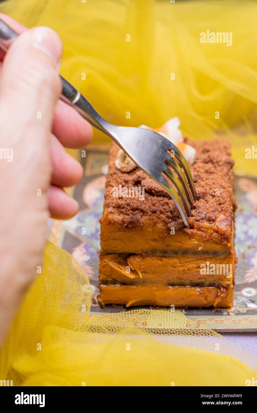 Eine männliche Hand, die einen Schokoladenkuchen mit einer Gabel packt. Stockfoto